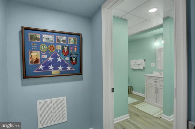 hallway featuring light wood-type flooring, a sink, and baseboards