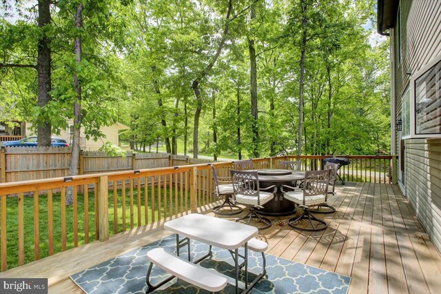 wooden terrace with outdoor dining space and fence