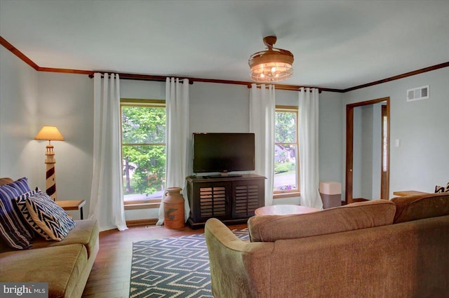 living area featuring plenty of natural light, wood finished floors, crown molding, and baseboards