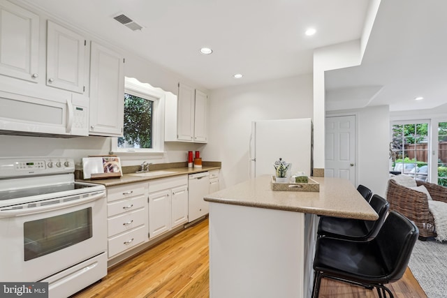 104 E Oxford Ave, Alexandria, VA 22301 - kitchen with white appliances, a sink, a breakfast bar, light wood finished floors, and a center island
