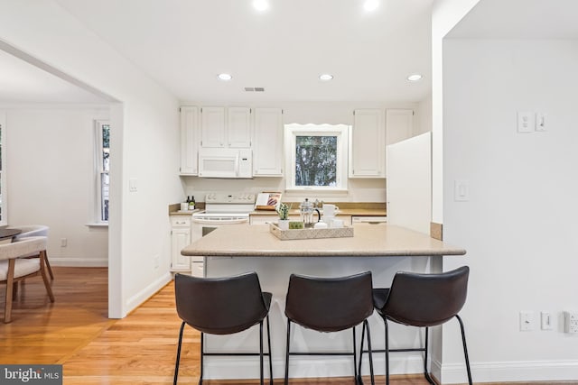 104 E Oxford Ave, Alexandria, VA 22301 - kitchen with white appliances, a kitchen bar, white cabinetry, light countertops, and recessed lighting