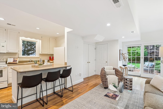 104 E Oxford Ave, Alexandria, VA 22301 - kitchen with white appliances, light wood finished floors, a kitchen breakfast bar, white cabinetry, and light countertops