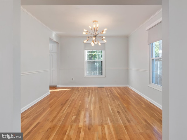 empty room featuring a chandelier, light wood-type flooring, crown molding, and baseboards