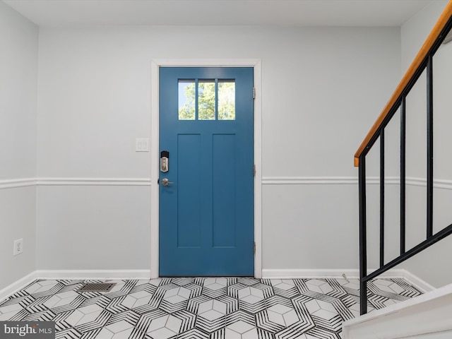 entryway featuring tile patterned floors, baseboards, and stairway