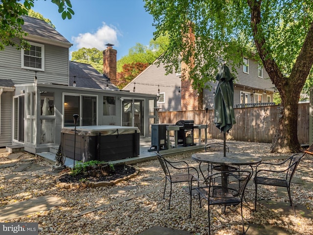 rear view of property featuring a hot tub, a chimney, fence, a patio, and outdoor dining space
