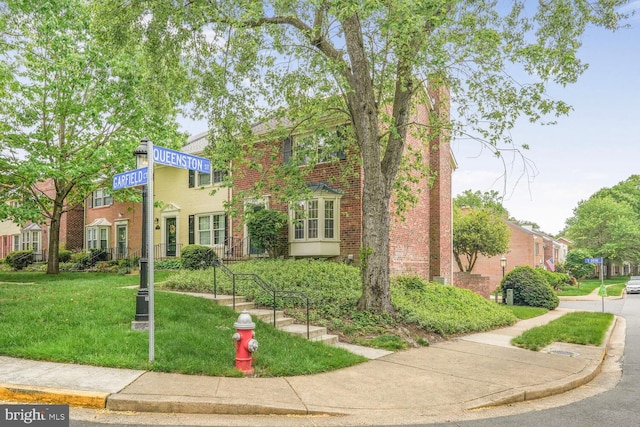 multi unit property featuring brick siding and a front lawn