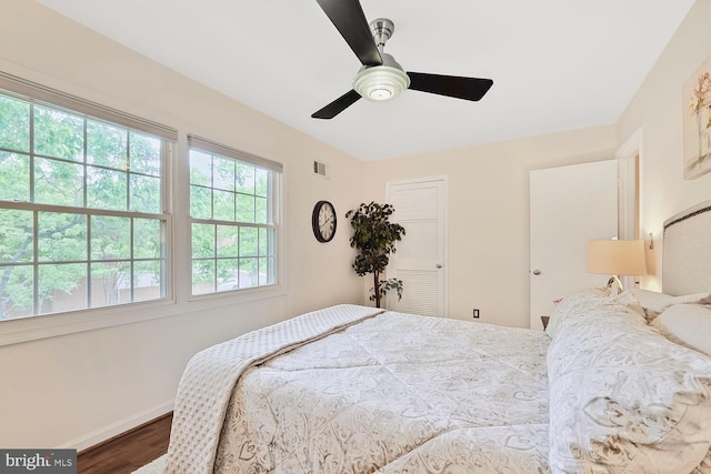 bedroom with wood finished floors, baseboards, a ceiling fan, and a closet