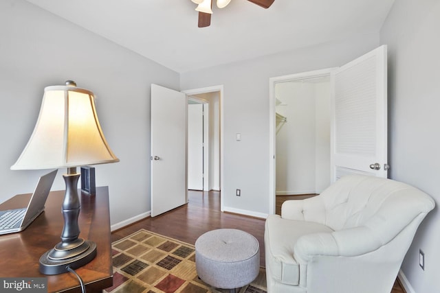 living area with a ceiling fan, wood finished floors, and baseboards
