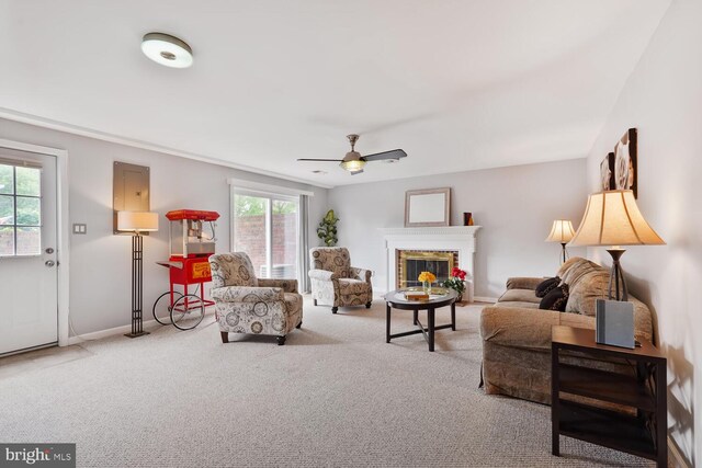 living area featuring carpet, a fireplace, baseboards, and a ceiling fan