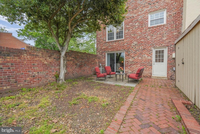 back of house featuring fence, a patio area, and brick siding