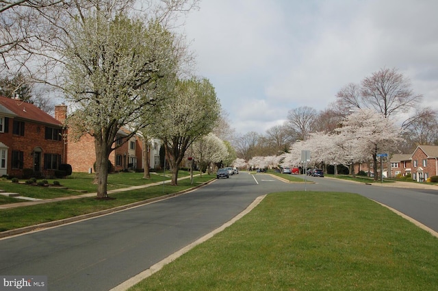 view of asphalt road featuring sidewalks, a residential view, and curbs