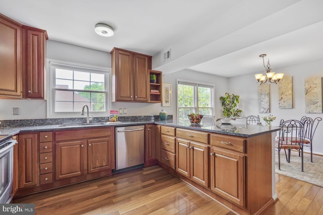 kitchen featuring a sink, stainless steel appliances, hardwood / wood-style floors, a peninsula, and a chandelier