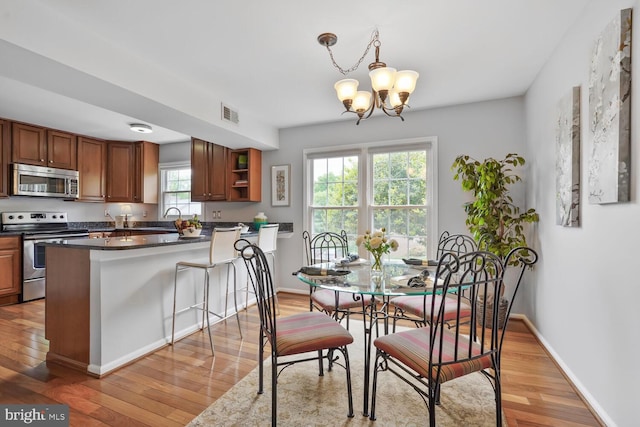 dining space with light wood-type flooring, a chandelier, and baseboards