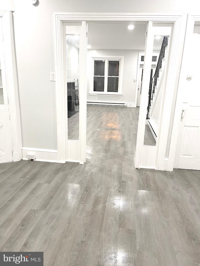 111 Oley St, Reading, PA 19601 - hallway with baseboards, wood finished floors, stairway, and a baseboard heating unit