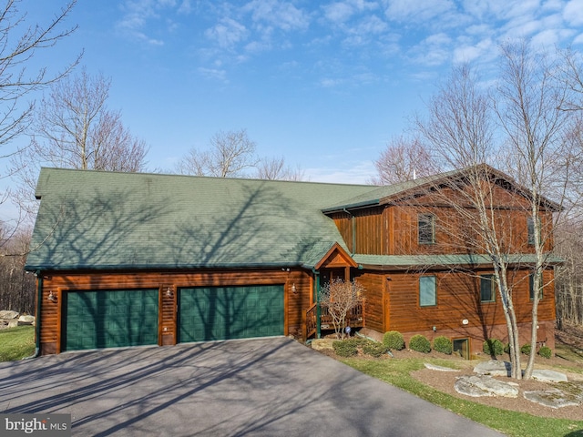view of front of home with driveway, a garage, and roof with shingles