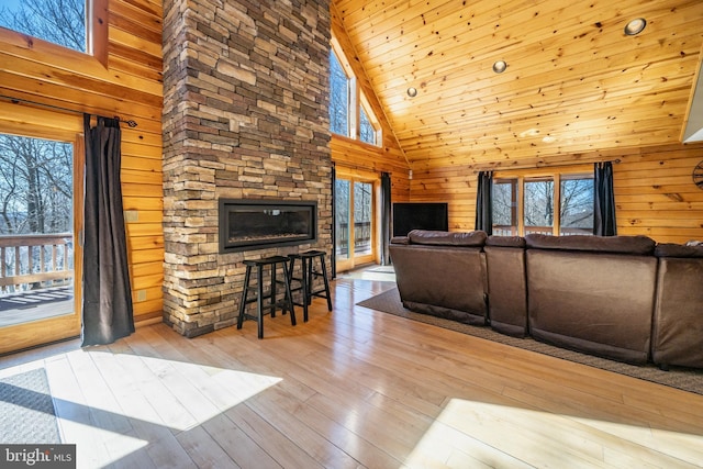 living area with healthy amount of natural light, high vaulted ceiling, wood walls, wood-type flooring, and wood ceiling