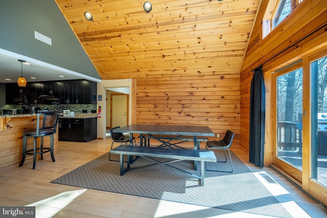 dining room with high vaulted ceiling, plenty of natural light, wooden walls, wooden ceiling, and light wood-type flooring