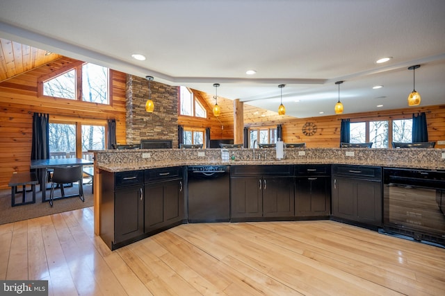 kitchen with black dishwasher, wine cooler, healthy amount of natural light, vaulted ceiling, and wooden walls
