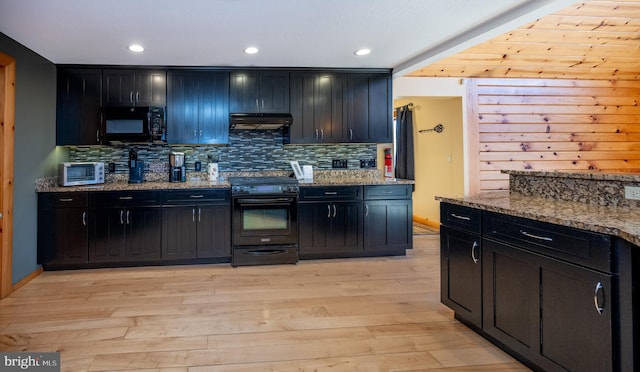 kitchen featuring black appliances, under cabinet range hood, dark cabinets, backsplash, and recessed lighting
