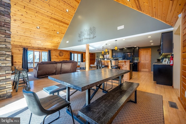dining area with high vaulted ceiling, light wood-style floors, recessed lighting, wooden ceiling, and wooden walls