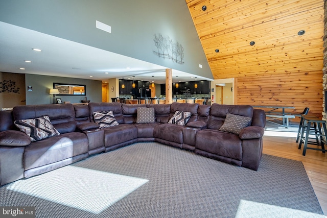 living room with high vaulted ceiling, wood finished floors, recessed lighting, a dry bar, and wooden walls
