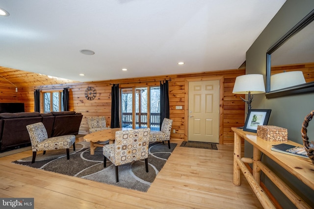living room featuring light wood-type flooring, recessed lighting, lofted ceiling, and wood walls