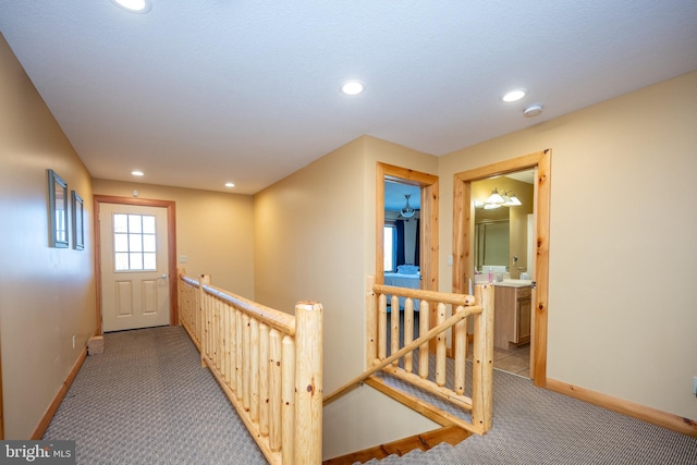 hall featuring an upstairs landing, light colored carpet, recessed lighting, and baseboards