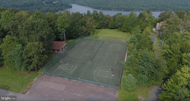 view of sport court with a water view, community basketball court, and a wooded view