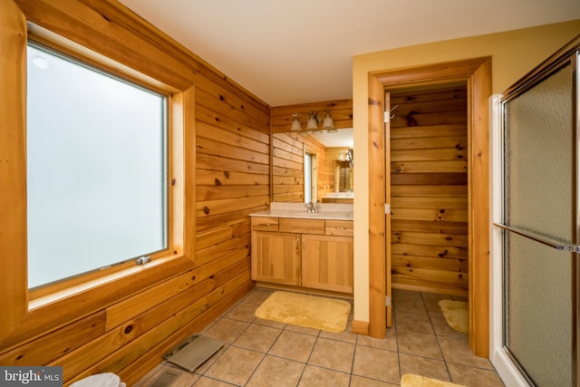 full bath featuring wooden walls, a stall shower, vanity, tile patterned floors, and plenty of natural light