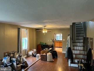living area featuring a ceiling fan, dark wood-type flooring, stairs, and baseboards