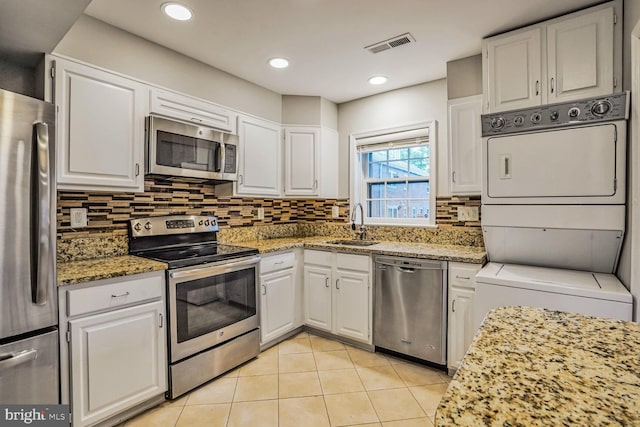 6630 Hillandale Rd Unit 56, Chevy Chase, MD 20815 - kitchen with appliances with stainless steel finishes, stacked washer / dryer, a sink, and white cabinetry