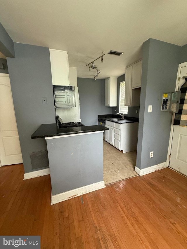 2503 Kent Town Pl Unit 2503B, Hyattsville, MD 20785 - kitchen with dark countertops, white cabinets, baseboards, and light wood-style flooring