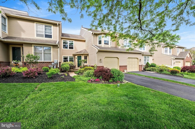 townhome / multi-family property with brick siding, asphalt driveway, a front yard, and a garage