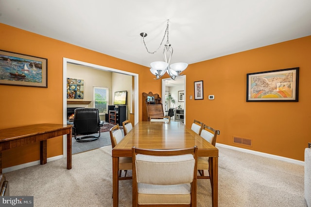 dining space with a chandelier, light carpet, and baseboards