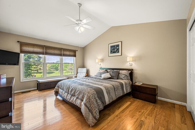 bedroom with vaulted ceiling, light wood-style flooring, baseboards, and a ceiling fan