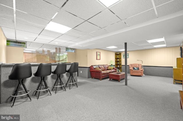 carpeted living area featuring bar and a drop ceiling