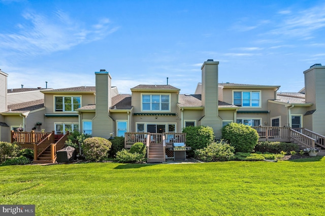 rear view of property with stairway, a wooden deck, a lawn, and a chimney