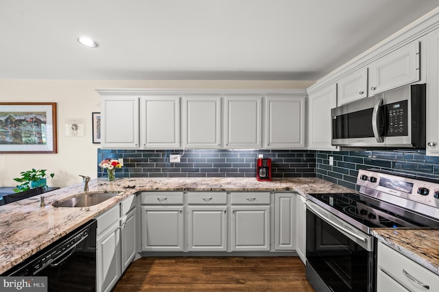 kitchen with appliances with stainless steel finishes, a sink, decorative backsplash, white cabinetry, and recessed lighting