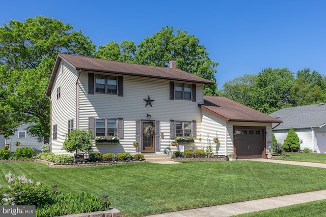colonial-style house with an attached garage, a chimney, a front yard, and driveway