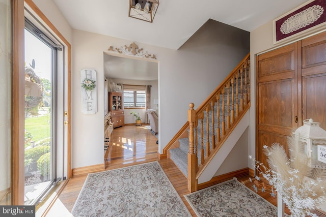entrance foyer with stairs, light wood-style flooring, and baseboards
