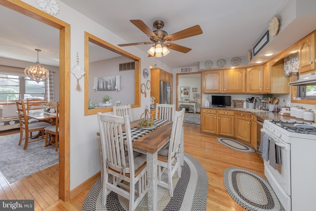 kitchen with white gas range oven, light wood-style flooring, under cabinet range hood, a ceiling fan, and a chandelier