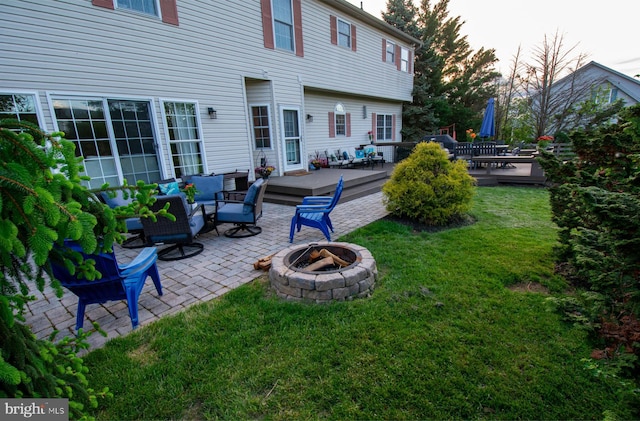 rear view of property featuring an outdoor living space with a fire pit, a patio, a yard, and a deck