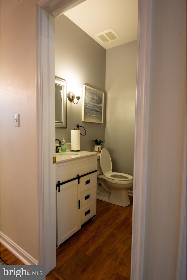 bathroom featuring toilet, vanity, and wood finished floors
