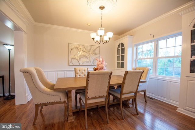 dining area featuring a decorative wall, a chandelier, crown molding, dark wood-style flooring, and wainscoting