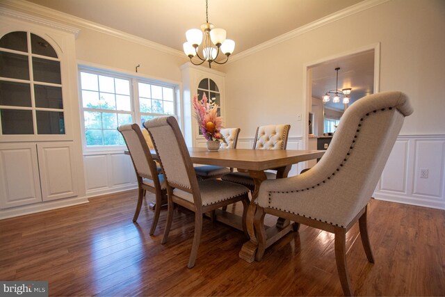 dining area featuring a chandelier, a decorative wall, wood finished floors, ornamental molding, and wainscoting
