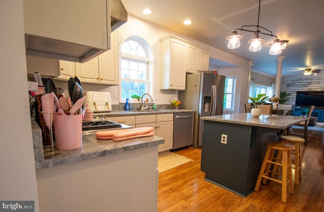 kitchen with stainless steel appliances, a sink, plenty of natural light, light wood finished floors, and recessed lighting