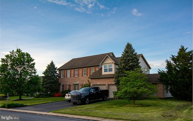 view of front of house with asphalt driveway, an attached garage, brick siding, and a front lawn