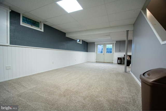 below grade area featuring a paneled ceiling, carpet floors, and wainscoting