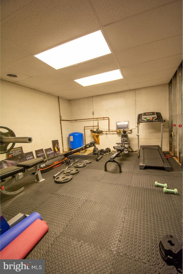 exercise room featuring a drop ceiling and concrete block wall