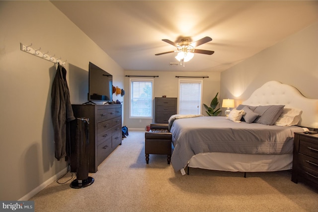 bedroom with light colored carpet, baseboards, and a ceiling fan